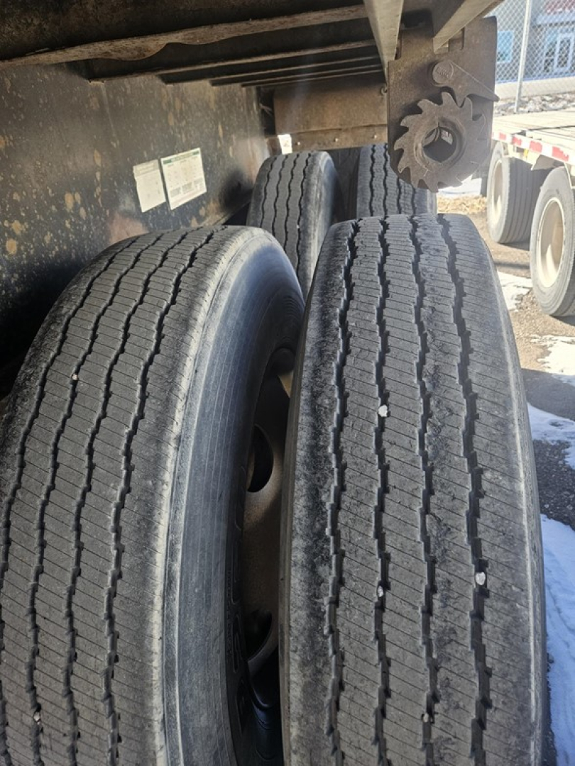 Trailer axle area showing dual rear tires on Fruehauf steel flatbed.