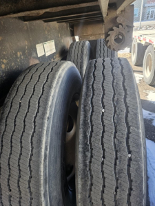 Trailer axle area showing dual rear tires on Fruehauf steel flatbed.