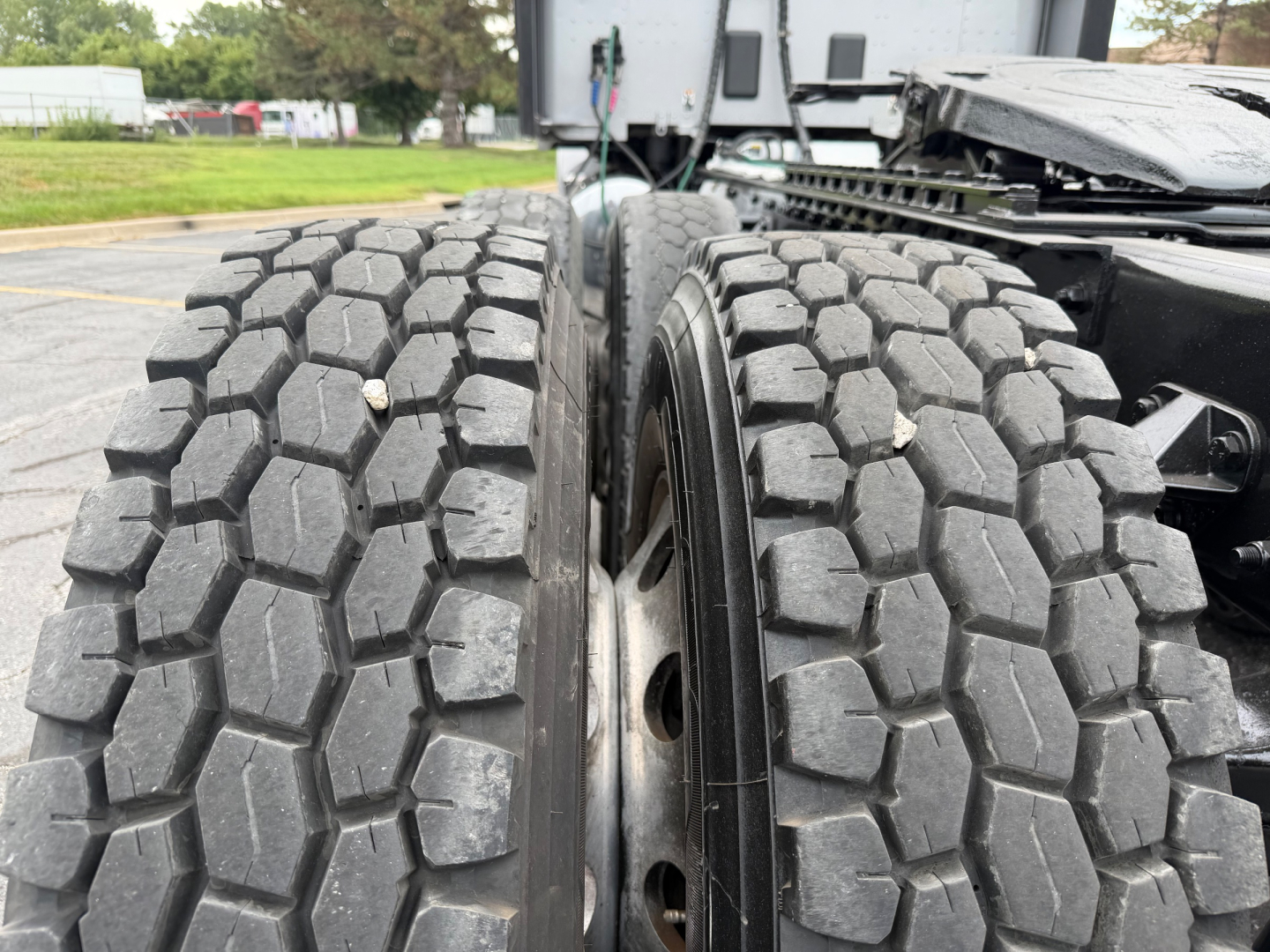 Dual rear truck tires on a 2018 Kenworth T680 showing heavy tread blocks and wheel rims.