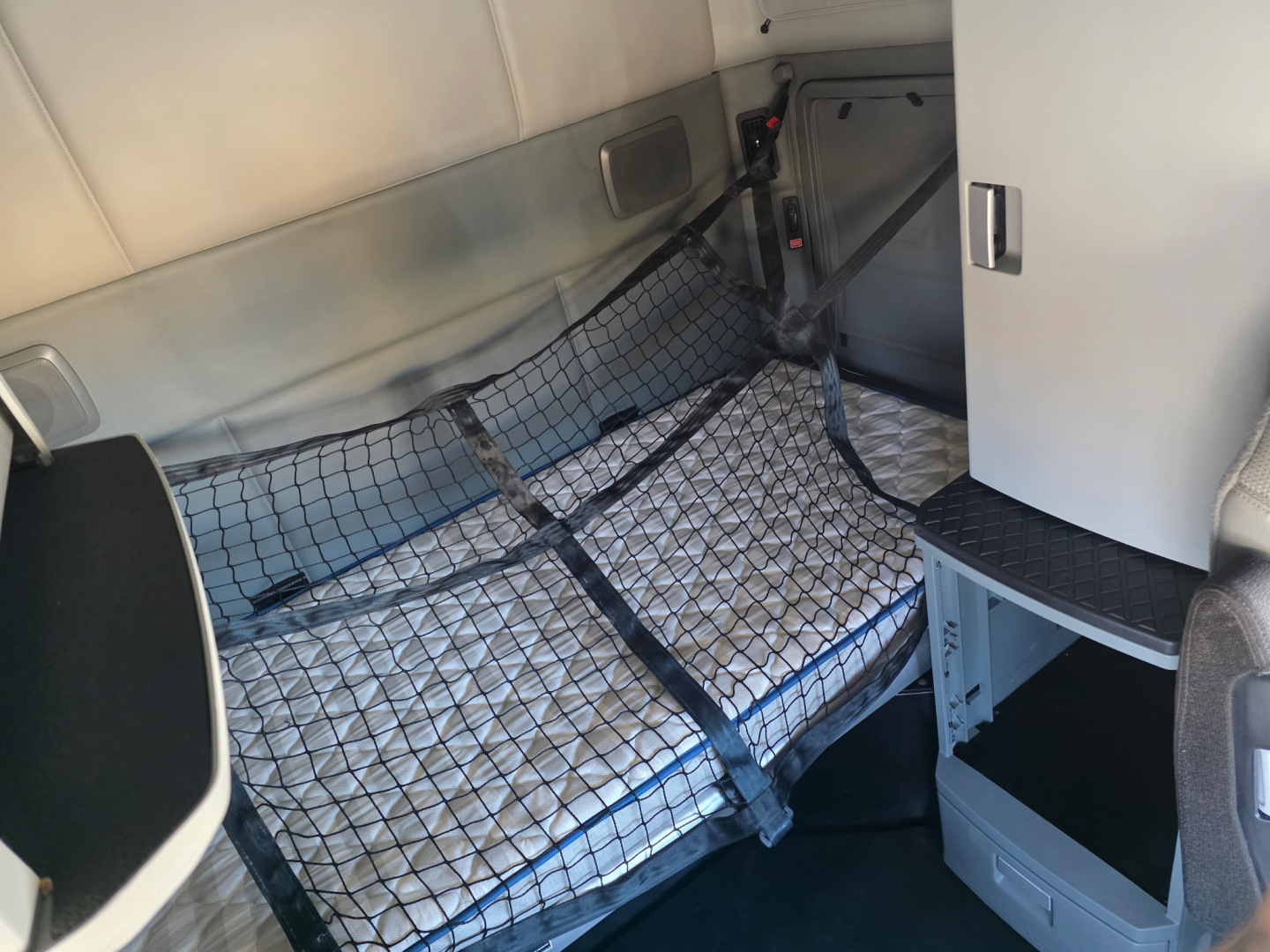 Kenworth T680 sleeper cab interior showing storage net and bunk area with quilted mattress