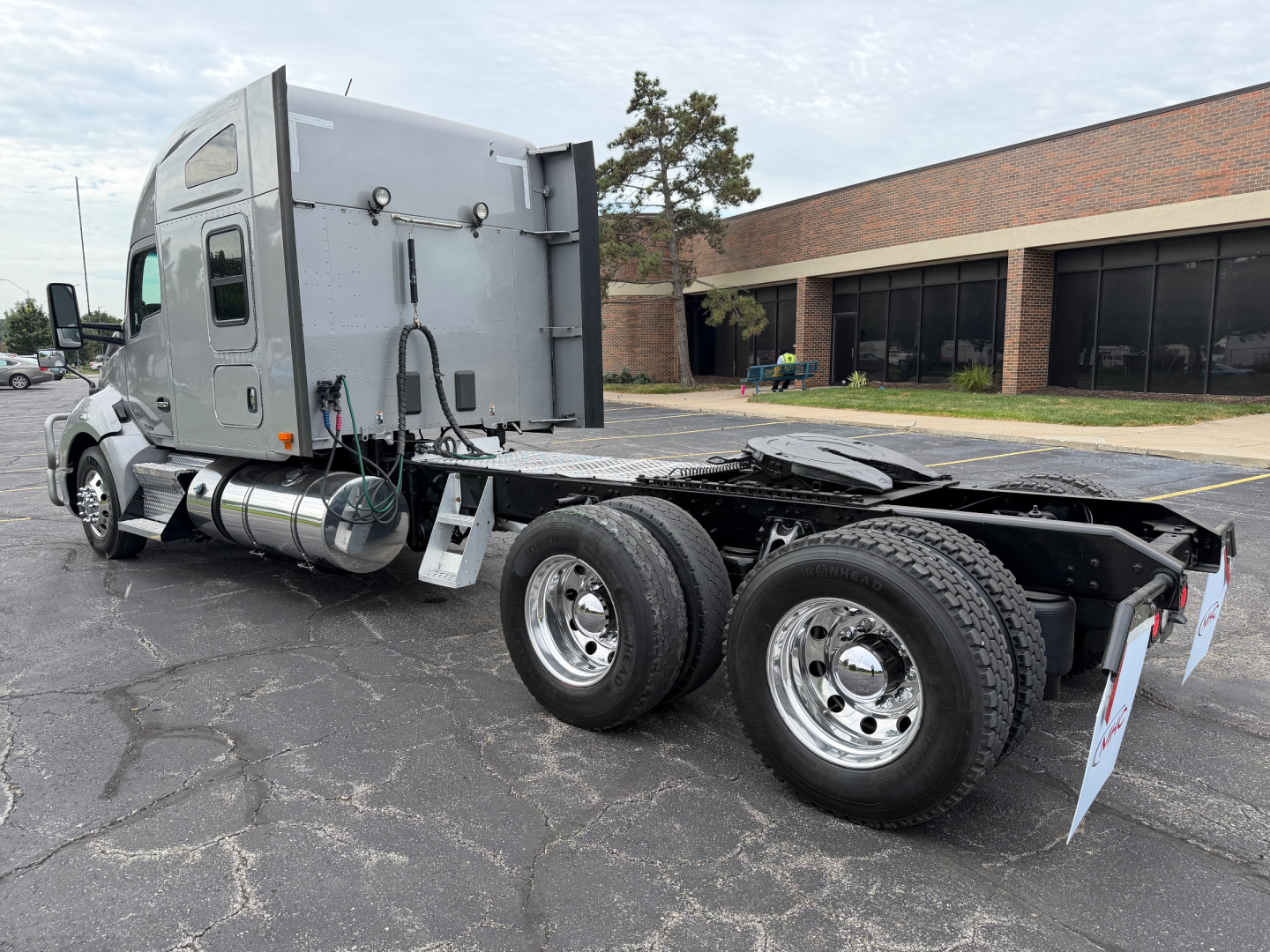 Kenworth T680 tractor sleeper cab side view showing dual rear wheels and chassis, gray exterior, fuel tanks, and rear mud flaps.