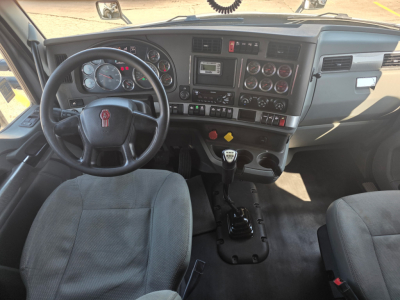 Kenworth T680 cab interior showing steering wheel, dash gauges, center console, and manual gear shifter.