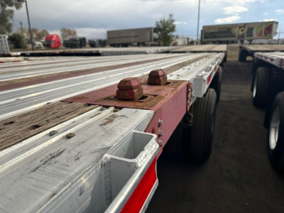 Flatbed trailer edge with wear marks and red mounting lugs, Fontaine Infinity trailer in a truck lot.