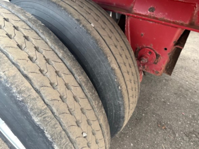 Trailer wheel and dual tires on Fontaine Infinity flatbed trailer showing tread and dirt with red chassis