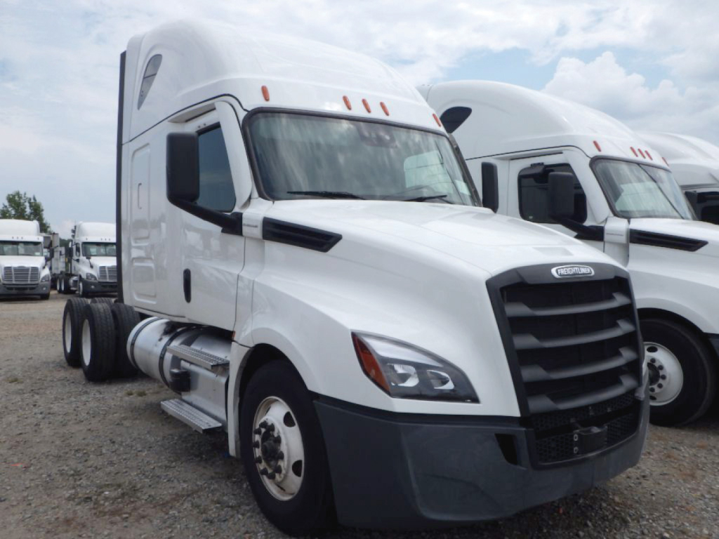 Freightliner Cascadia126 tractor cab with white exterior and black grille; side mirrors and sleeper window visible; front bumper and headlights; other trucks in background