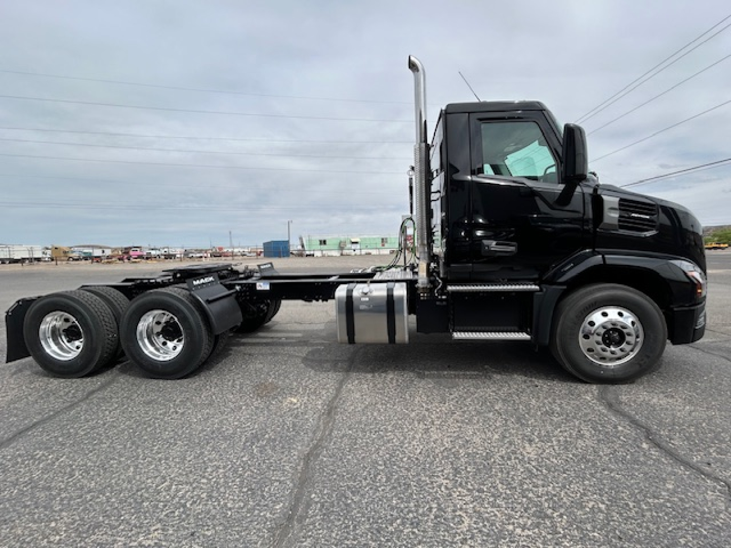 Truck side view showing a black 2027 Mack AN64T conventional daycab with dual rear axles and chrome exhaust stack.