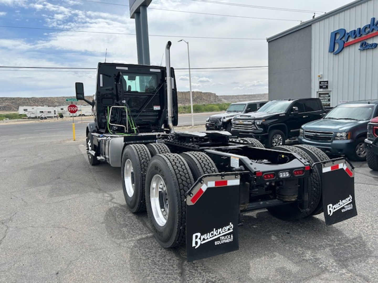 Mack AN64T tractor body and rear chassis showing dual rear axles and mud flaps with Brackett’s branding in a dealership lot.