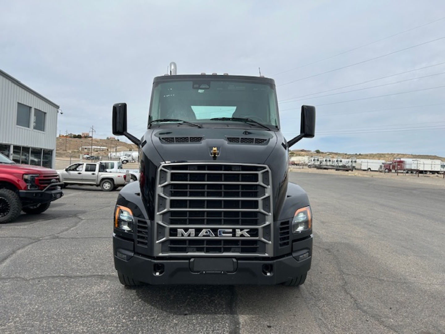 Front view of a black 2027 Mack AN64T conventional daycab truck showing bold front grille with MACK emblem and large bumper.
