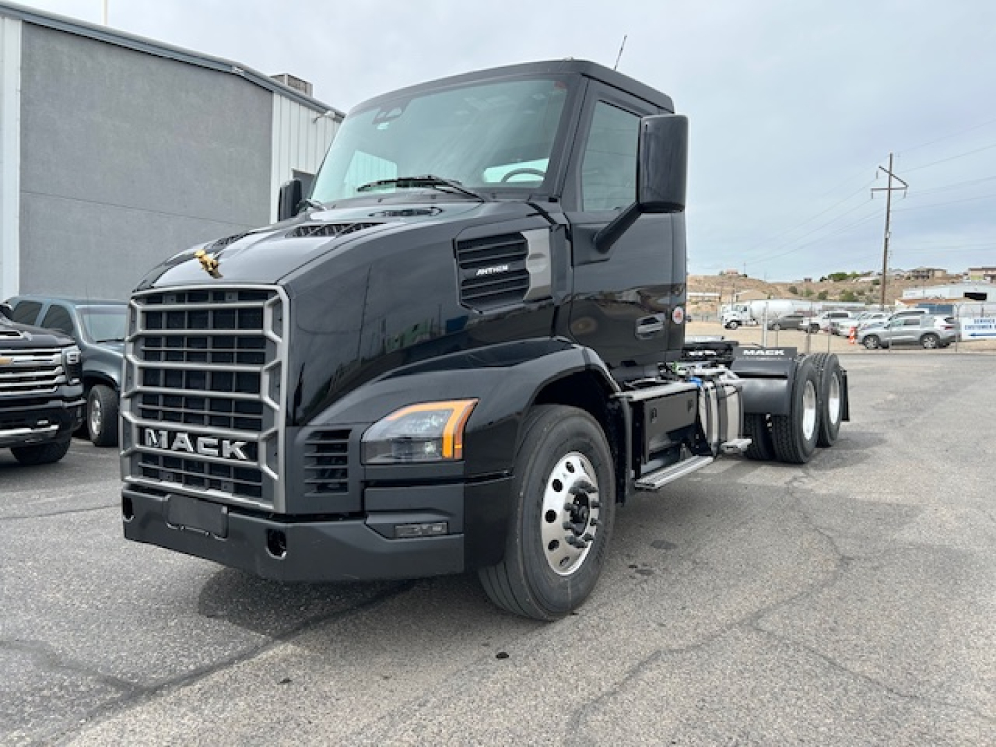 Mack AN64T conventional daycab truck front-left view showing grille, bumper, headlights, and cab with black exterior.