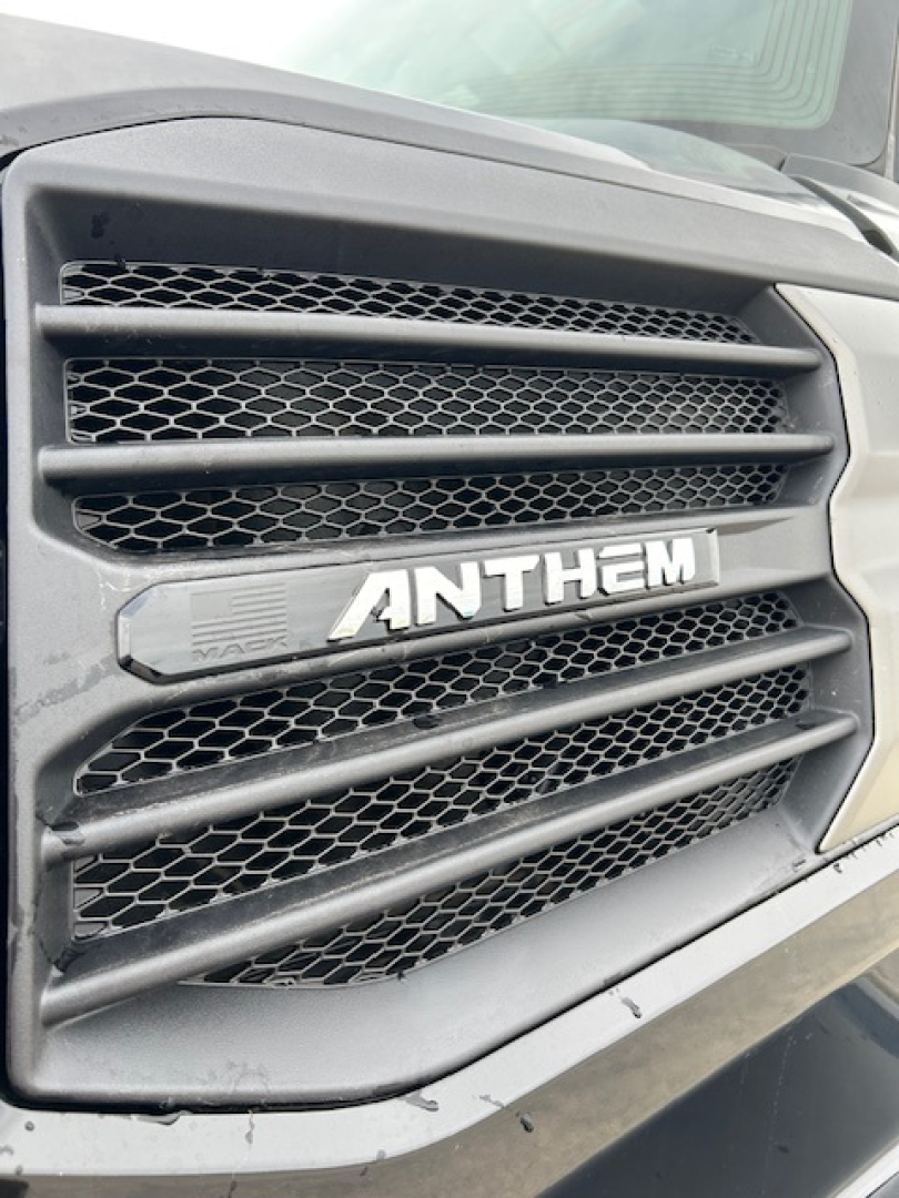 Vehicle front grille with ANTHEM badge on Mack truck and surrounding vents.