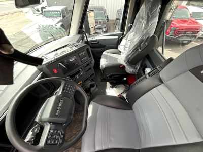 Cab interior of a new 2027 Mack AN64T daycab truck showing steering wheel, dashboard, and seats wrapped in plastic.
