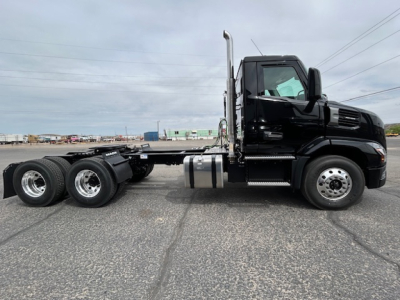 Truck side view showing a black 2027 Mack AN64T conventional daycab with dual rear axles and chrome exhaust stack.