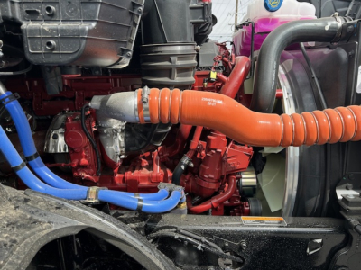 Mack AN64T engine bay showing bright orange intercooler pipe, blue coolant hoses, red engine block, and black radiator components.