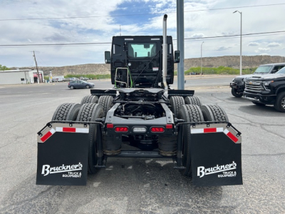 Rear view of a new Mack AN64T daycab tractor showing dual rear axles, mud flaps with Bruckner’s Truck & Equipment, and exposed fifth-wheel area.
