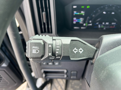 Steering column stalks in a Mack AN64T truck showing turn signal and headlight control levers with warning icons.