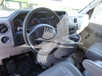 Interior of a 2011 Ford E450 cab showing steering wheel, dashboard gauges, and front seats from the driver’s side.
