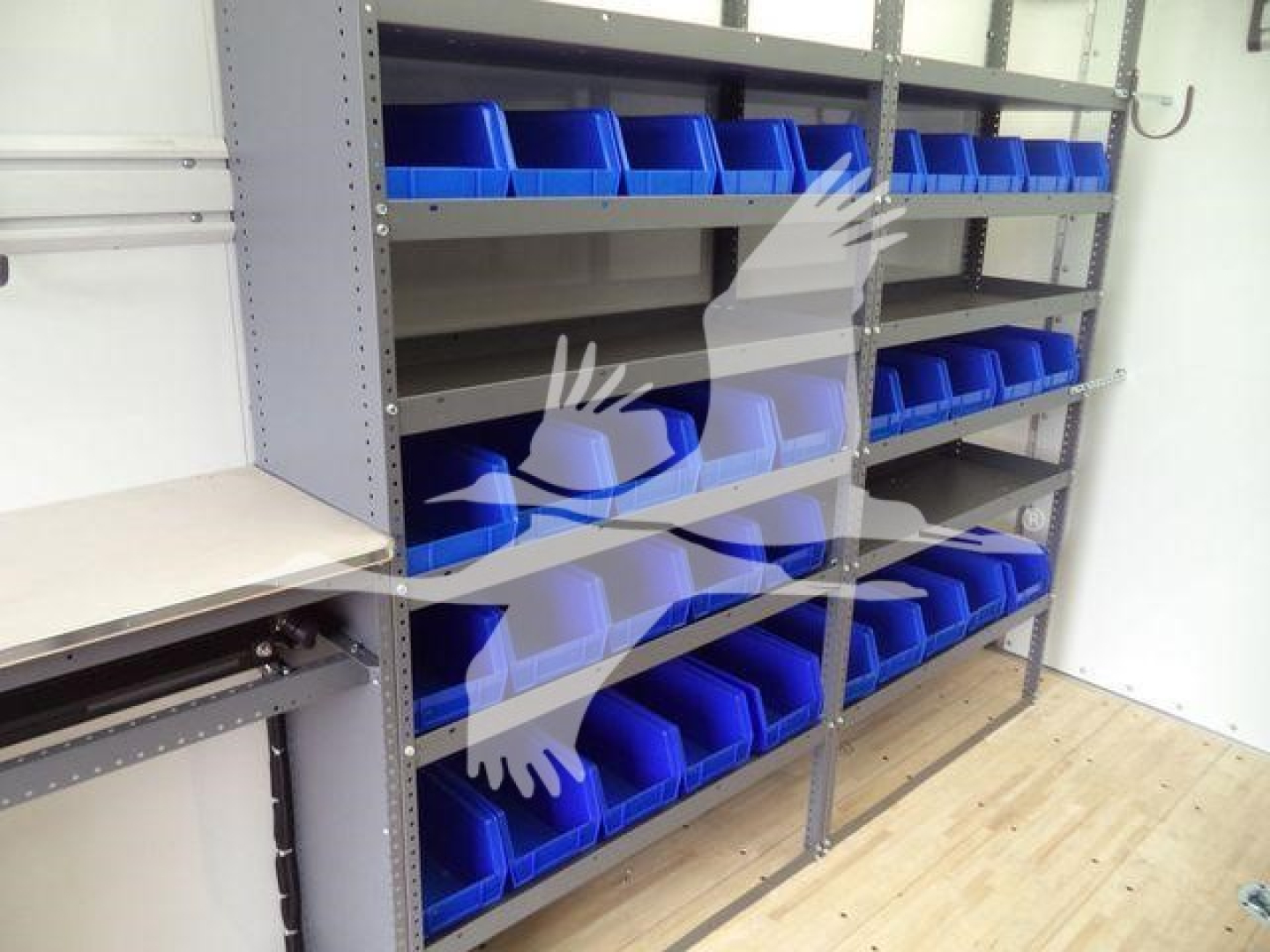 Box truck shelving with blue plastic bins in a workshop setting.