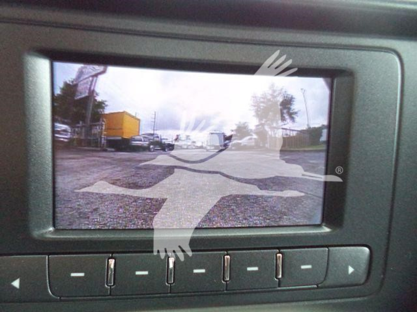 Vehicle display screen in a Chevrolet Silverado 6500HD showing a rear-view camera feed with a parking lot and vehicles.