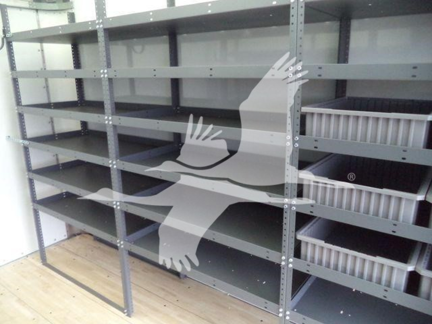 Warehouse-style metal shelving with multiple empty grey shelves and white plastic bins; part of an organized storage area.