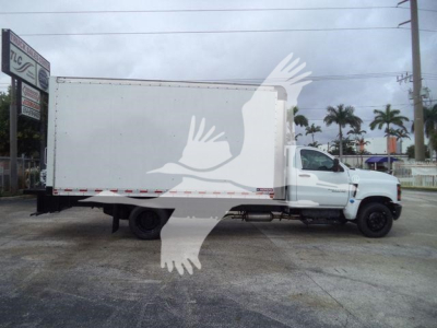 Box truck side view showing cargo box and cab, Chevrolet Silverado 6500HD size with long box, white exterior, at a dealership lot.