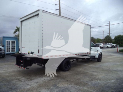 Box truck with a white cargo box on a flatbed chassis, rear view showing platform bumper and dual rear wheels, light gray sky in background.