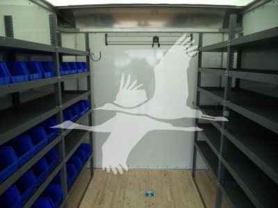 Truck cargo area with metal shelves and blue bins on left and right; wooden floor; white back wall.