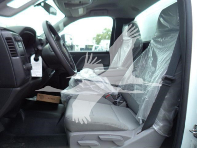 Truck interior showing steering wheel, front seats covered in plastic, and dashboard view of a 2023 Chevrolet Silverado 6500HD cabin.