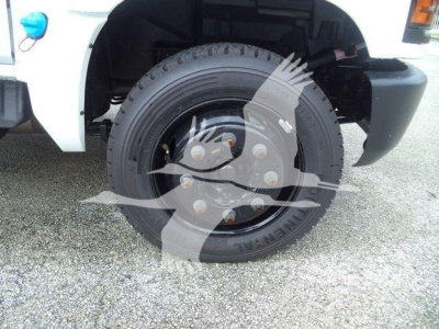 Front wheel and fender of a 2023 Chevrolet Silverado 6500HD box truck showing a steel wheel with lug nuts and tire; no visible branding text readable on the tire.