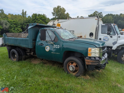Chevrolet Silverado 3500HD dump truck with plow, green body, number 203, side view, in a grassy lot.