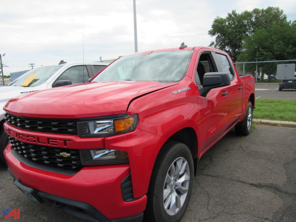 Chevrolet Silverado 1500 Limited pickup truck in red parked in a lot; front grille shows 'CHEVROLET' emblem; side badge 'Silverado' on front fender; black grille and headlight design visible.