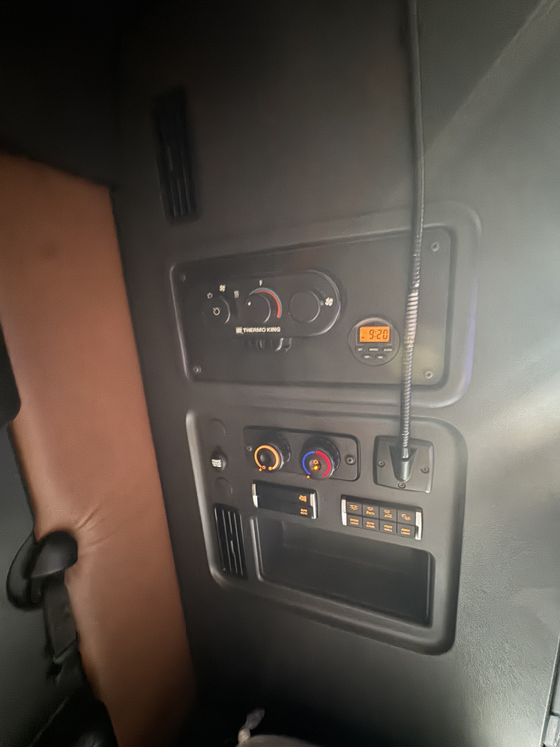 Dashboard controls and radio panel in Freightliner Cascadia 126 cab interior showing climate control dials and storage compartments.
