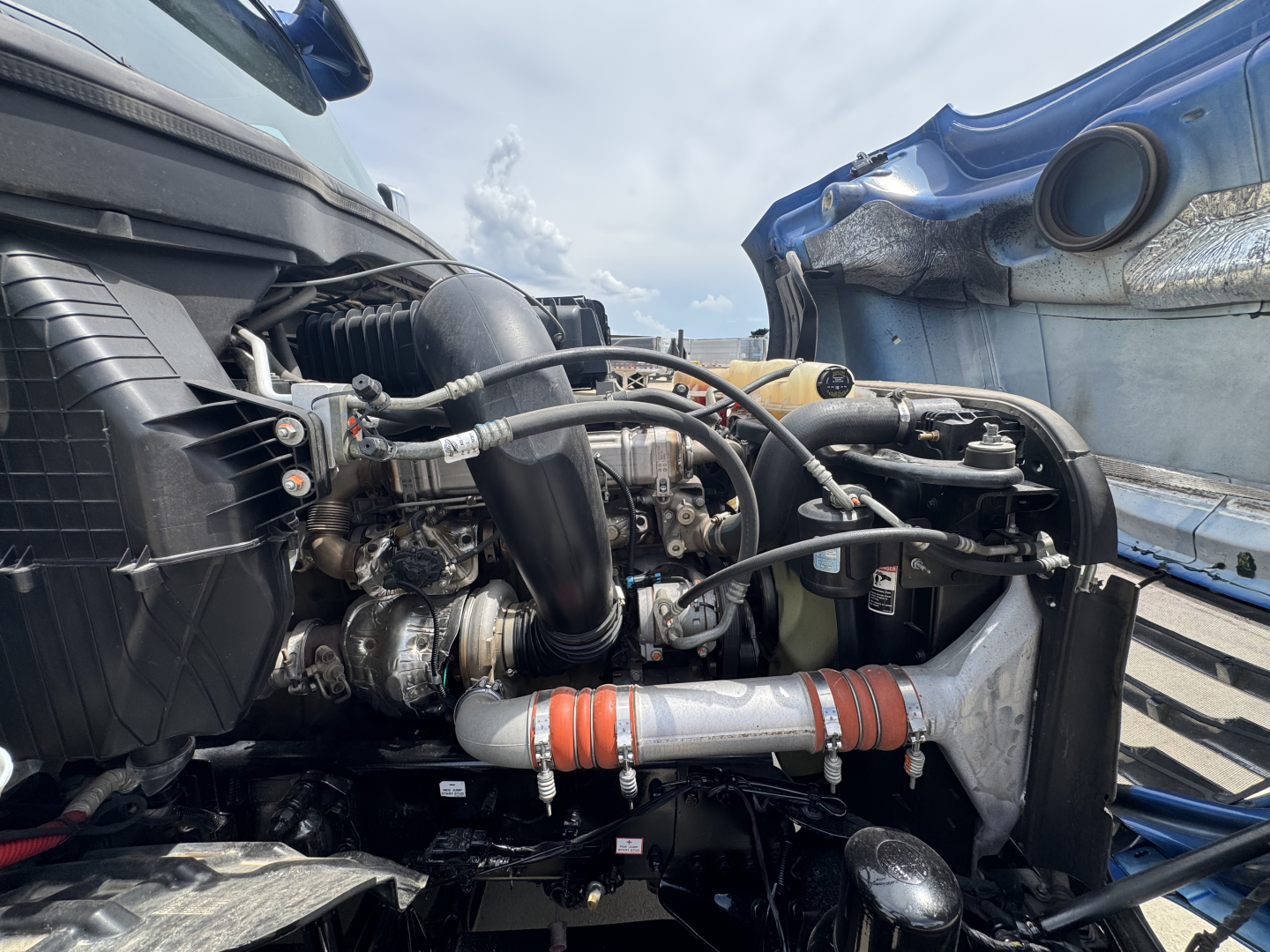 Truck engine bay view showing turbocharger and hoses in a Freightliner Cascadia 126 engine compartment.
