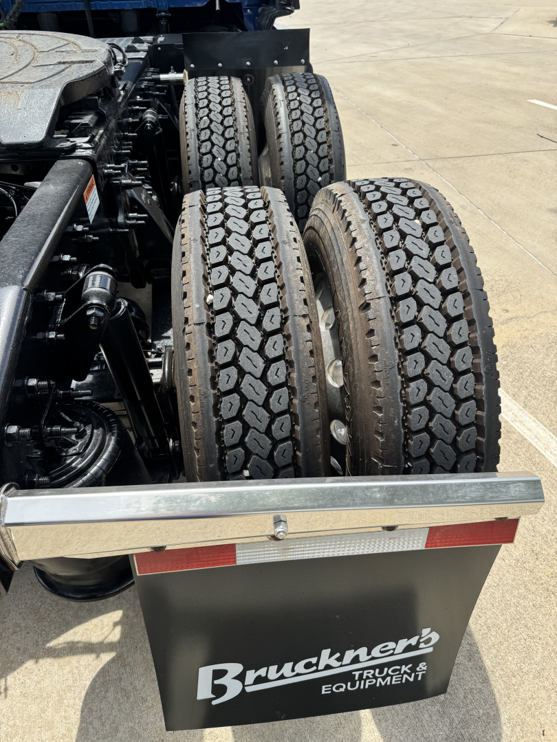 Rear view of a Freightliner Cascadia 126 truck chassis showing dual rear axles with heavy-duty tires, suspension components, and a Bruckner Truck & Equipment mudguard.