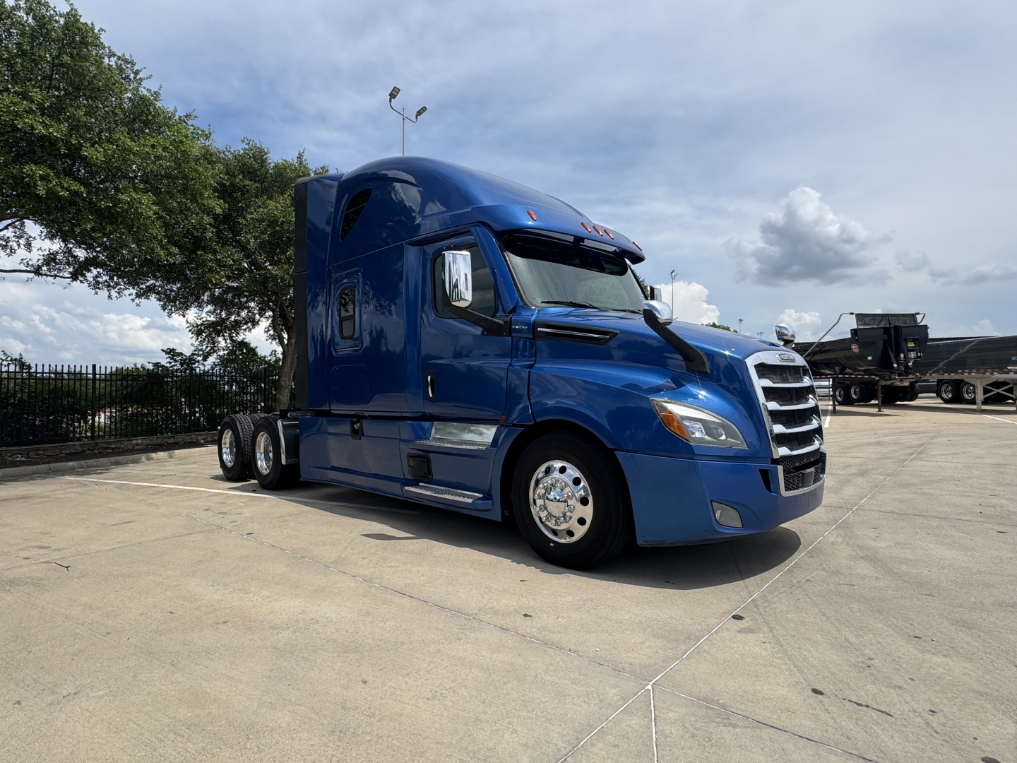 Freightliner Cascadia 126 tractor in blue, side view showing sleeper cab, front grille, chrome wheels, and dual rear axles.