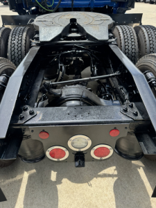 Rear view of a Freightliner Cascadia 126 tractor chassis showing fifth wheel, suspension, and Dual rear axles with exposed drivetrain and taillight area.