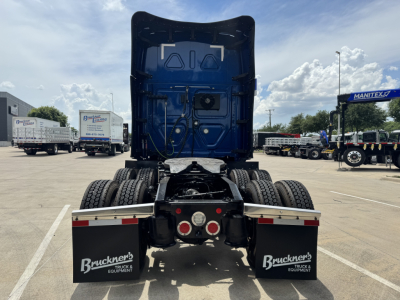 Rear view of a 2022 Freightliner Cascadia 126 in a truck lot showing dual rear axles, black chassis, and mudflaps with BrukeneR text. Visible cables and underbody components.