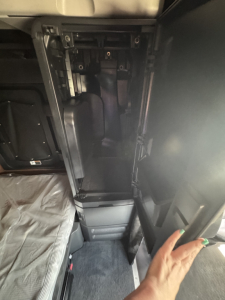 Freightliner Cascadia 126 sleeper cab interior showing dash-to-door area with open storage compartment and exposed framework.