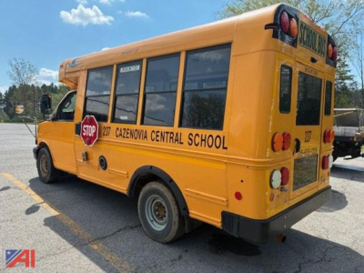School bus, rear three-quarter view, yellow, CAZENOVIA CENTRAL SCHOOL lettering on side, stop sign folded, black bumper, rear lights, school bus windows.