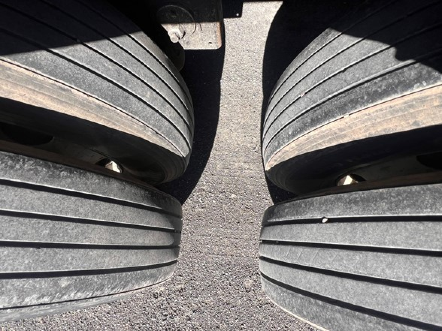 Trailer dual rear axles showing six large tires on a Stoughton grain trailer. No text visible.