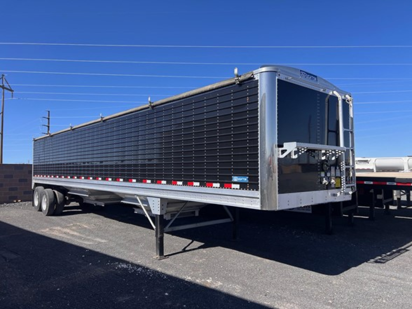 Stoughton grain trailer in-service showing hopper trailer with black side panels and front access area.