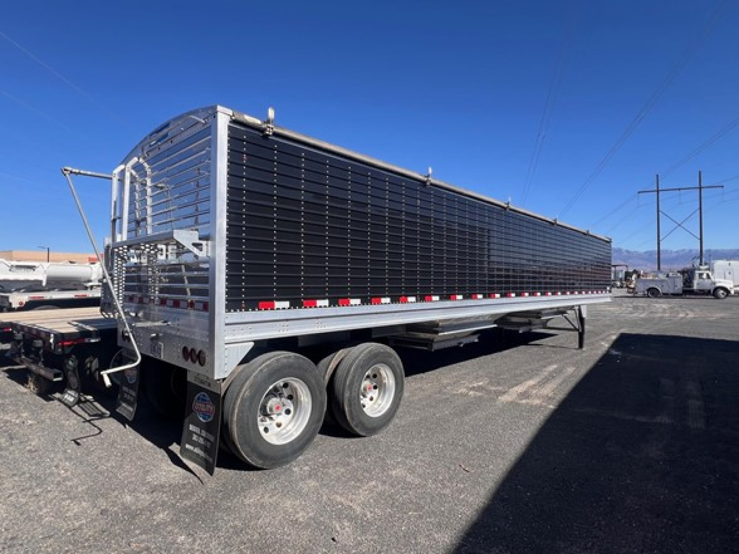 Stoughton grain trailer side view showing black hopper with chrome frame and tandem axles.