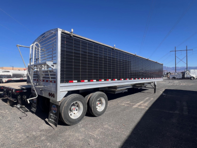 Stoughton grain trailer hopper with dual rear axles and black side panels showing a chrome framework.