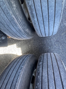 Trailer tires shown from above with wear lines, dual-axle configuration, no visible damage on sidewalls.