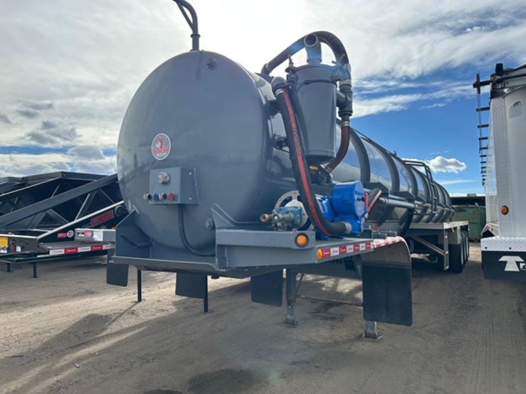 Vacuum tanker trailer in-service rear view showing circular rear tank with hoses and blue pump on right side.