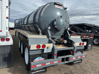 Rear view of a gray Dragon vacuum tanker trailer on a triple-axle chassis with reflective striping and rear lights.