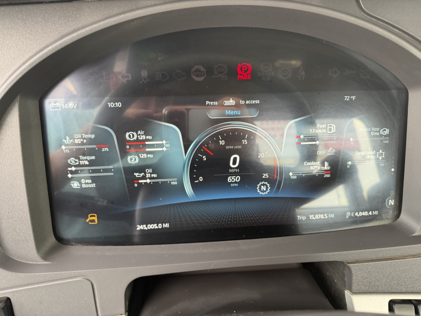 Dashboard display from a Kenworth truck showing digital gauges and icons including speedometer at 0, fuel, coolant, and trip data. Text visible: 10:10, 72 F, 0 MPH, 650, 14, Banda icons across top, odometer 245,005.0 MI, Trip 15,678.5 MI,