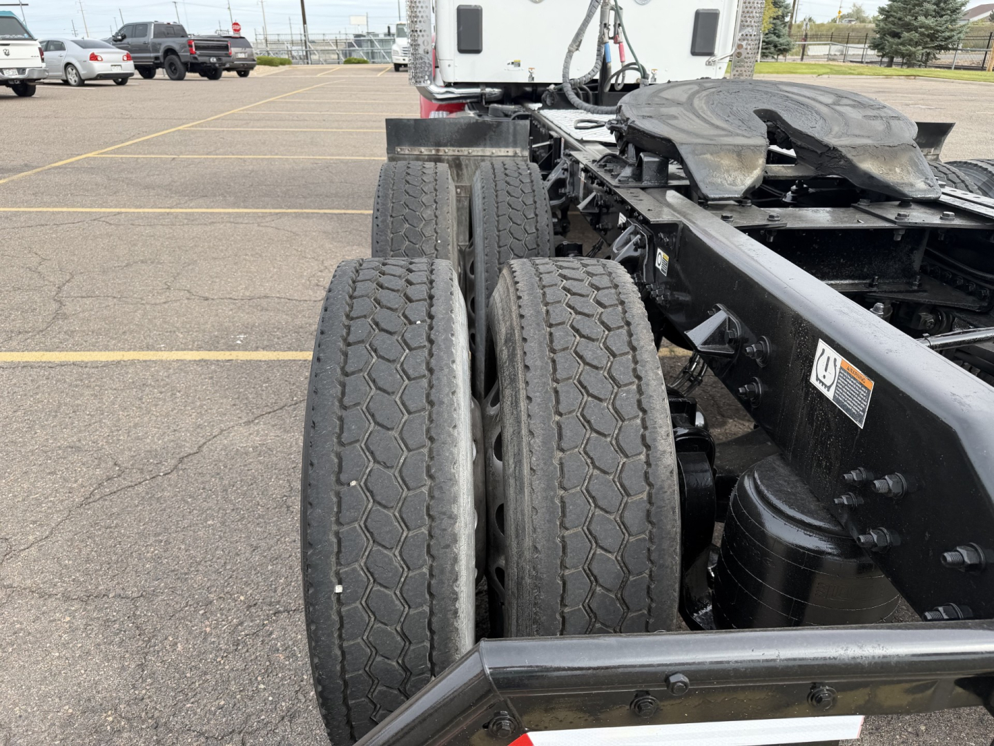 Kenworth T880 chassis showing dual rear axles and tire treads, with truck cab in background and parking lot lines.