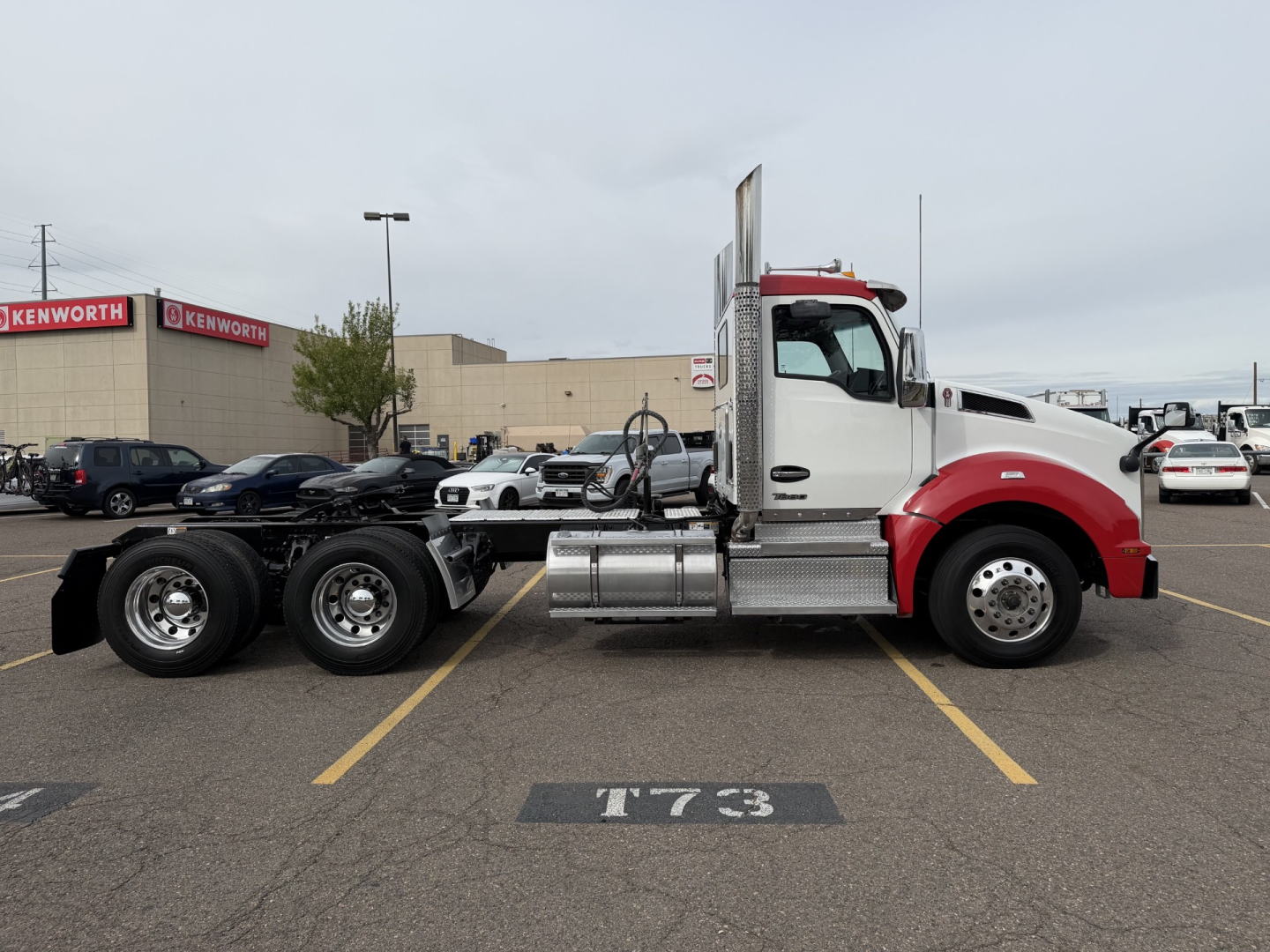 Kenworth T880 tractor in a parking lot side view showing fuel tanks and chassis; visible details include multiple wheel axles, exhaust stack, and cab; no legible model text visible on the image itself.