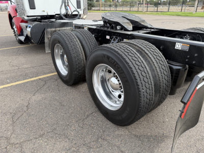 Kenworth T880 rear wheel area with dual rear axles and truck chassis visible, metal frame, tires, and fender area.