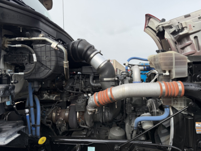 Kenworth T880 engine bay with visible hoses, pipes, and components. Text: none clearly legible; focus on engine and intake hoses.